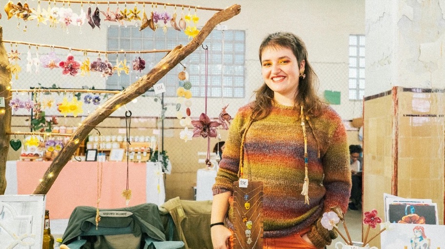 Artesã sorridente na sua banca de brincos e colares de flores